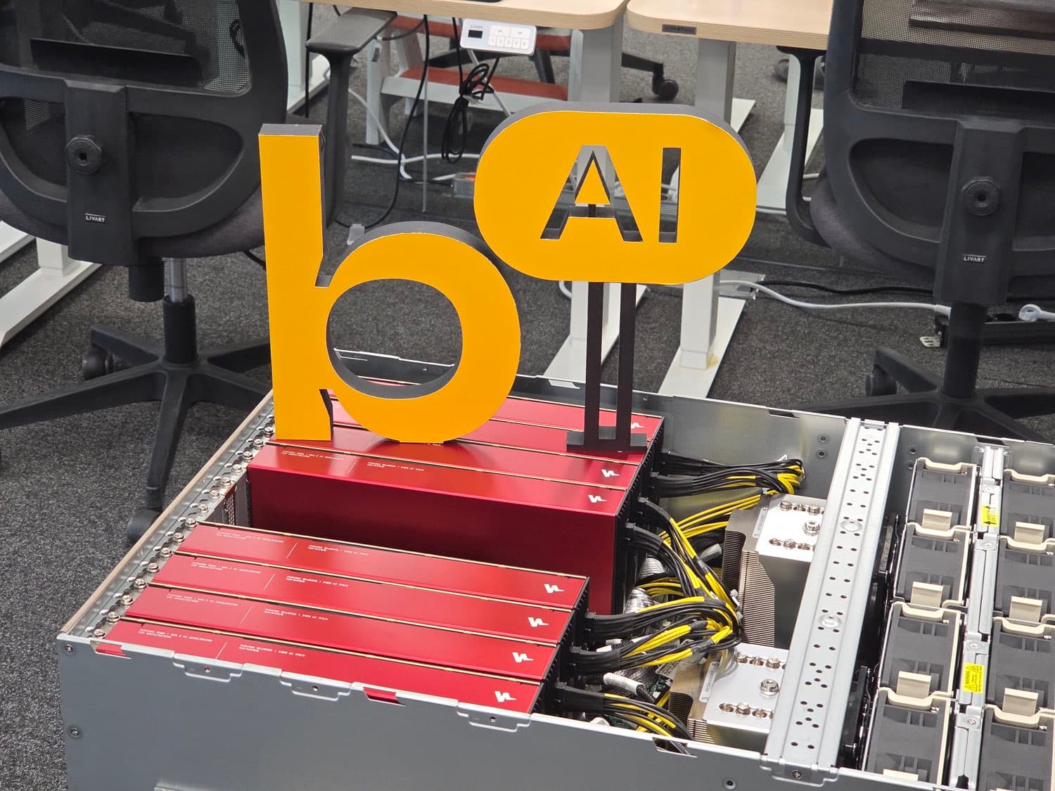 Backend.AI 로고 오브제가 놓인, 빨간 AI 가속기 카드가 장착된 열린 서버 섀시